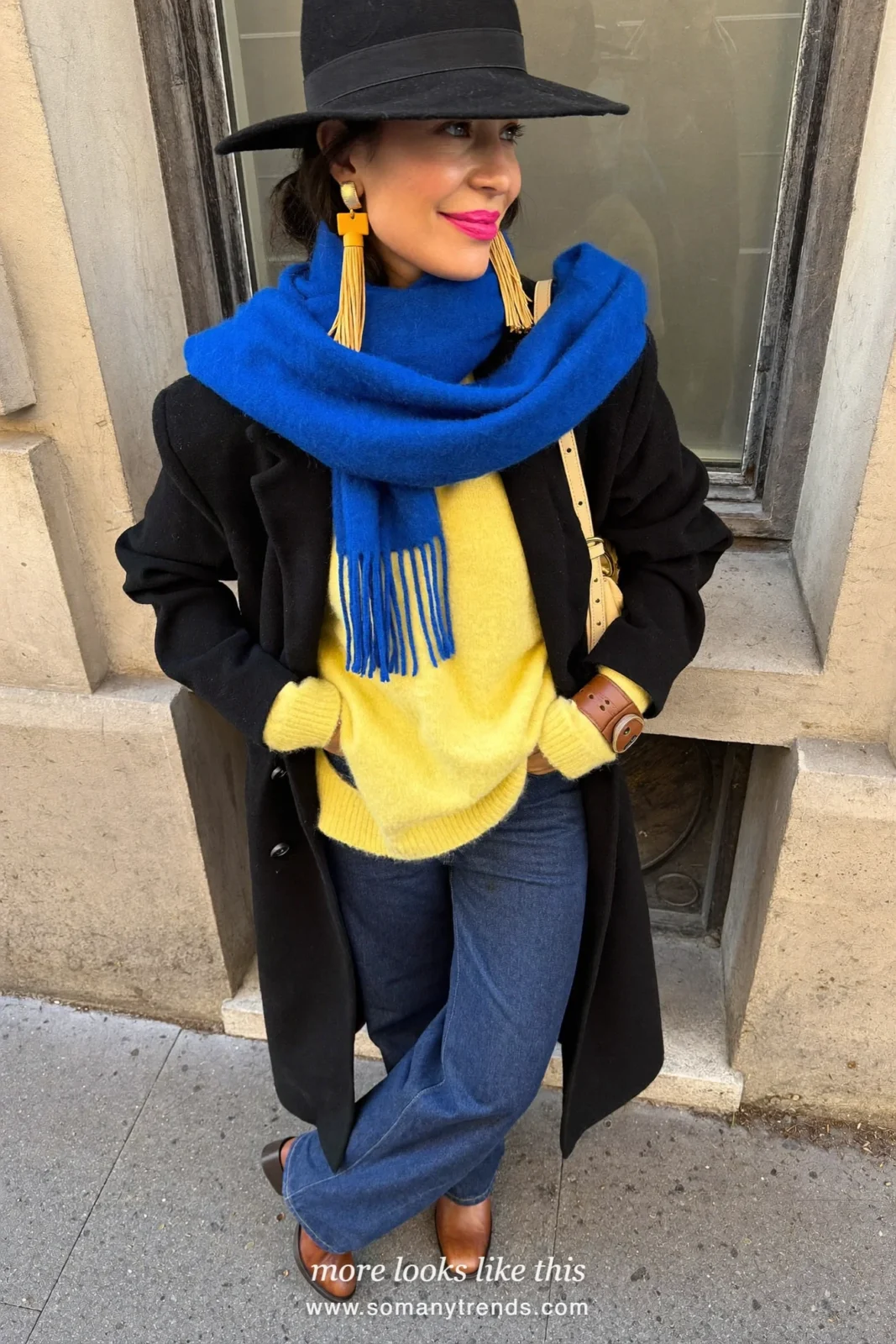 Woman in a lemon yellow cashmere sweater, dark blue wide-leg jeans, cobalt scarf and brown boots on a snowy street, outfit 20