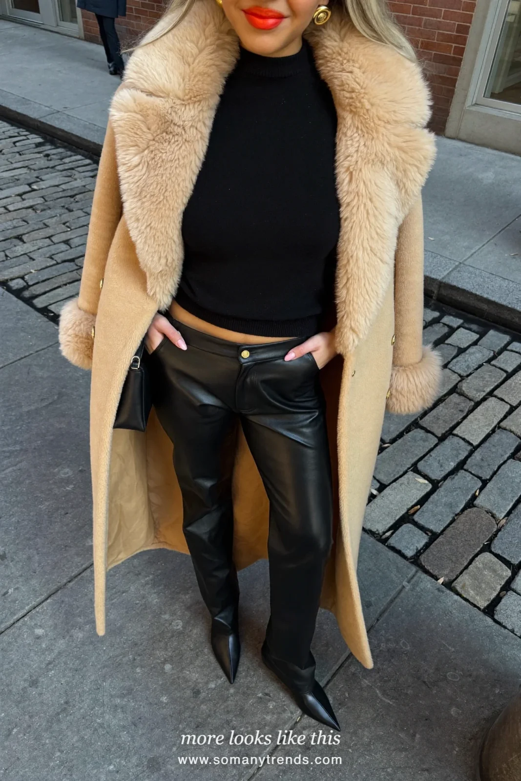 Woman in a long camel teddy coat over an all black outfit with black boots and a cobalt blue bag, look 5
