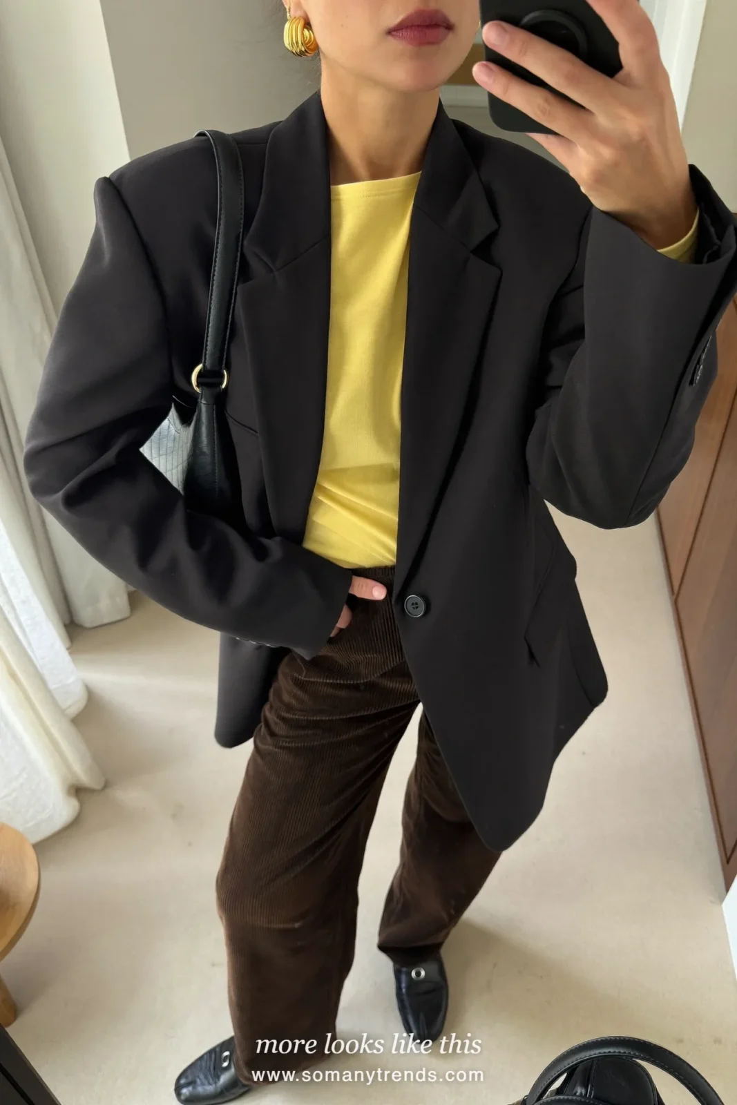 Woman in espresso brown corduroy wide-leg pants, a black blazer, a butter yellow top and black loafers, look 12