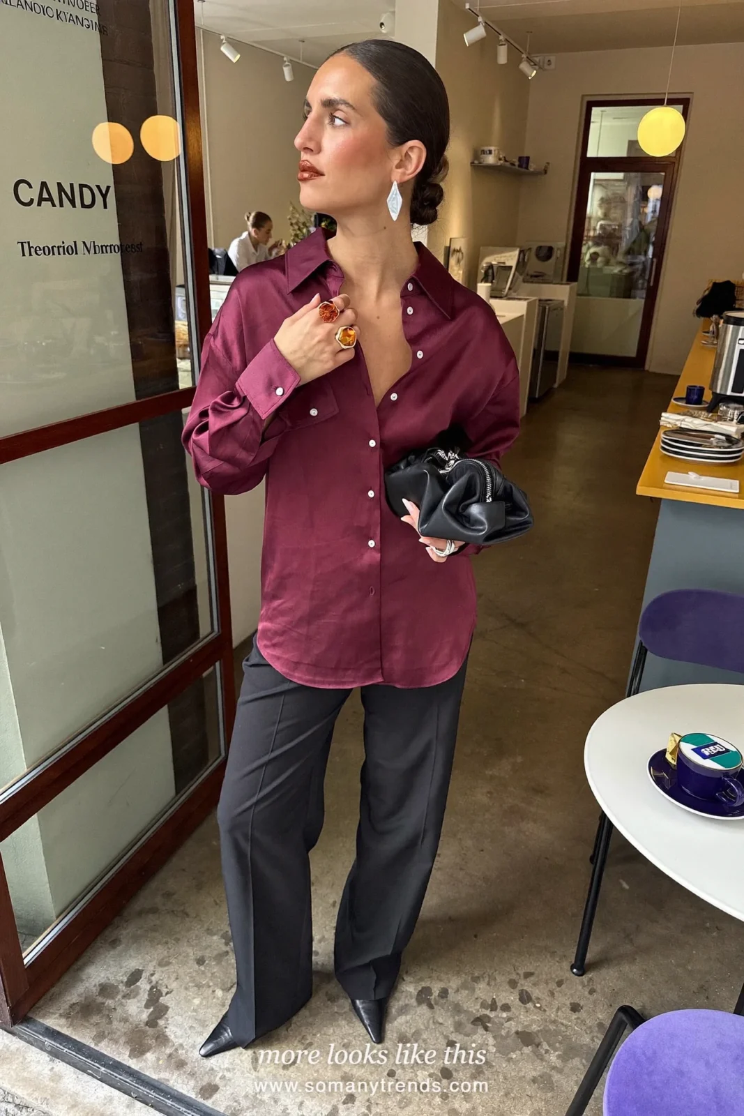 Woman in a burgundy satin shirt, black wide-leg tailored pants and black pointed boots with silver hoop earrings, outfit 13