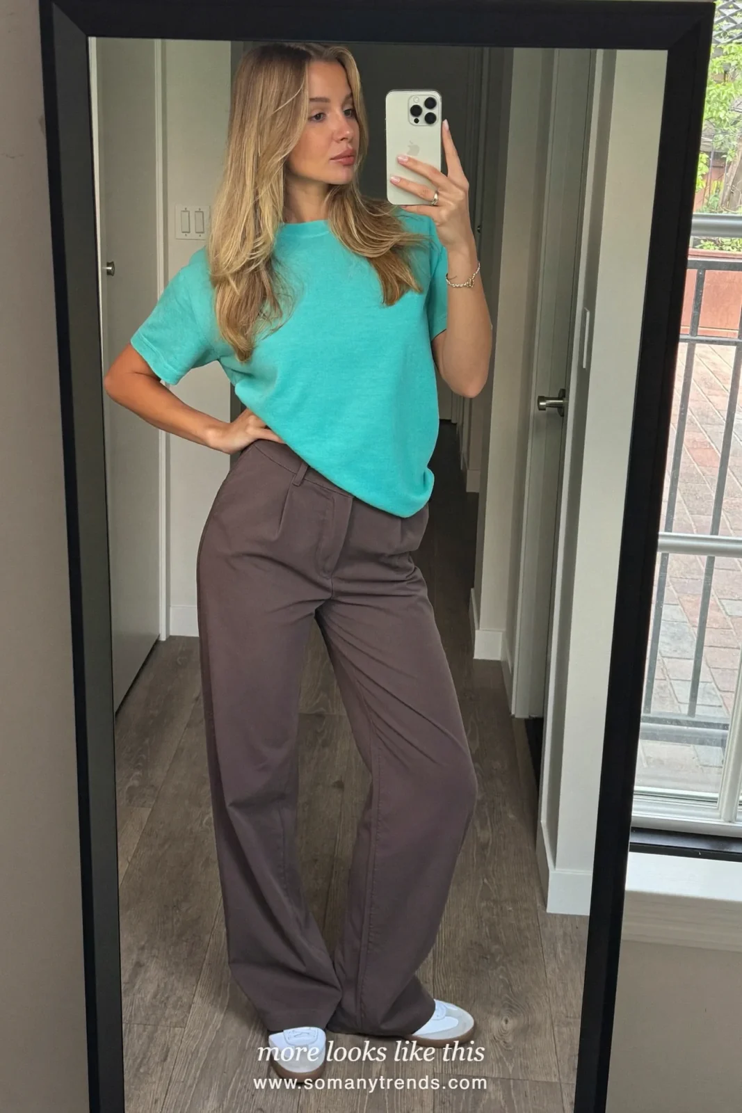 Woman in an aqua tee, chocolate brown wide pants, coral red bag and white sneakers, outfit 12
