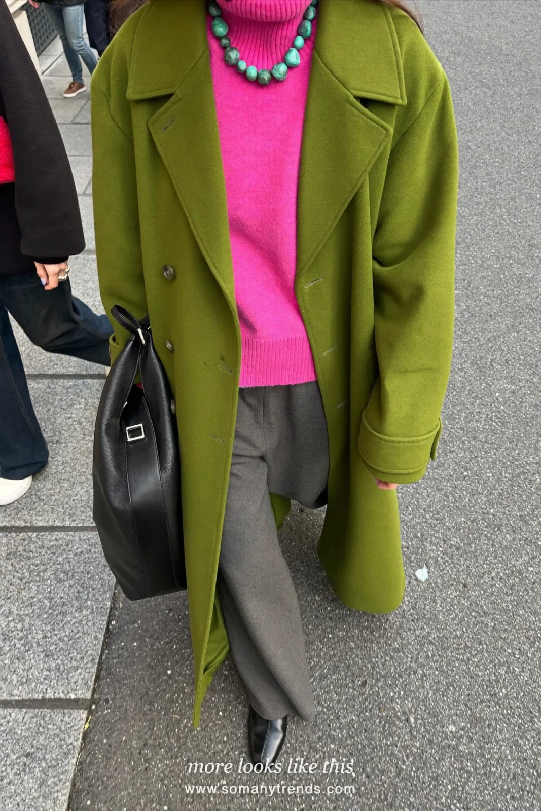 Woman in a long vivid moss green wool coat, bright pink turtleneck, gray wide-leg pants and black ankle boots, outfit 1