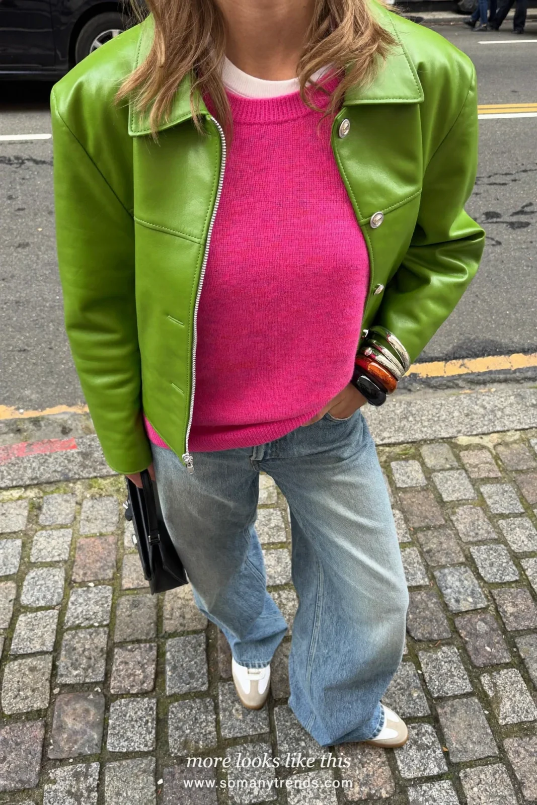 Woman in an olive green leather jacket, bright pink knit, white tee, light wide jeans and white sneakers, outfit 4