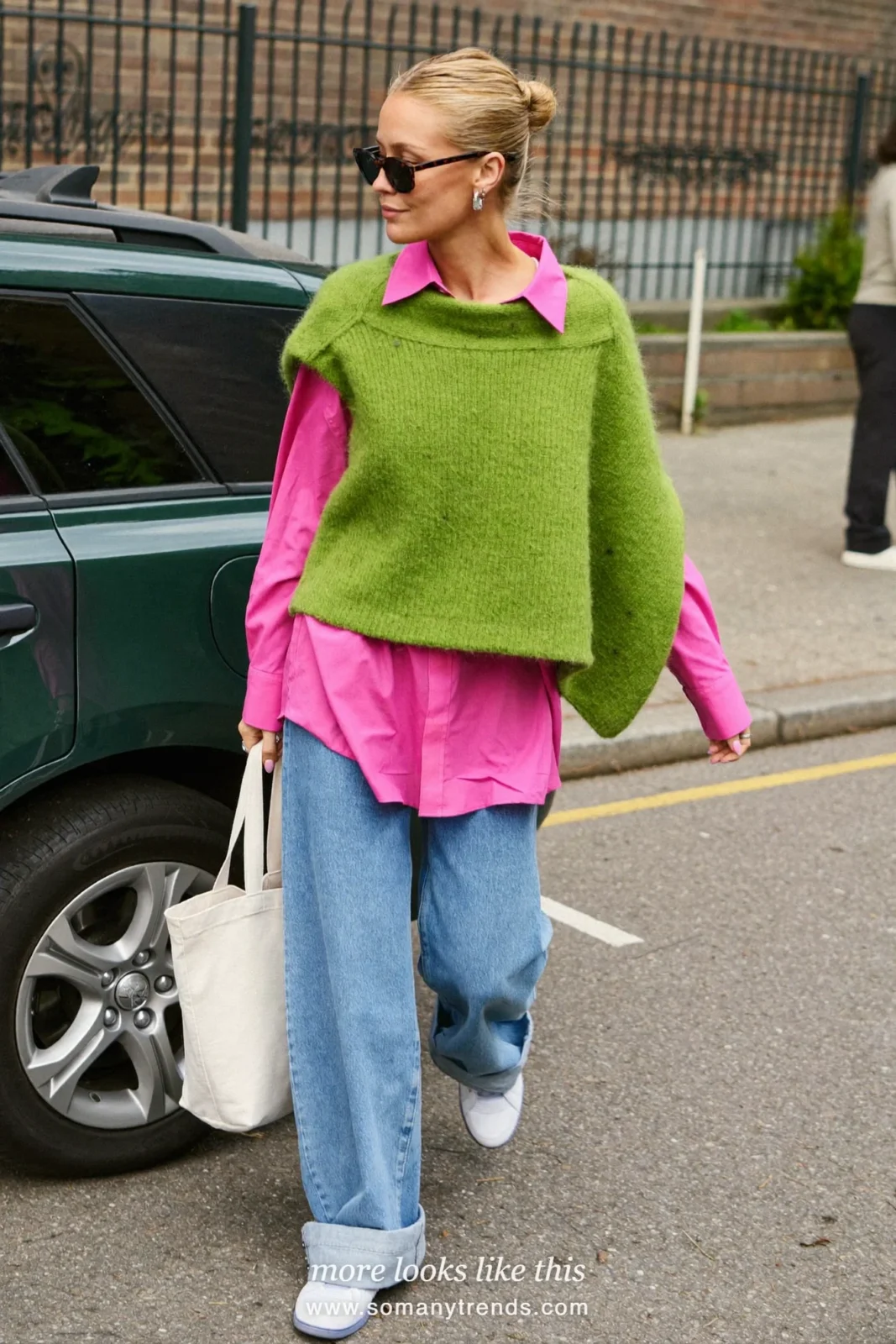 Woman in an oversized moss green sweater, bright pink oxford shirt, cuffed light jeans and white sneakers, outfit 8