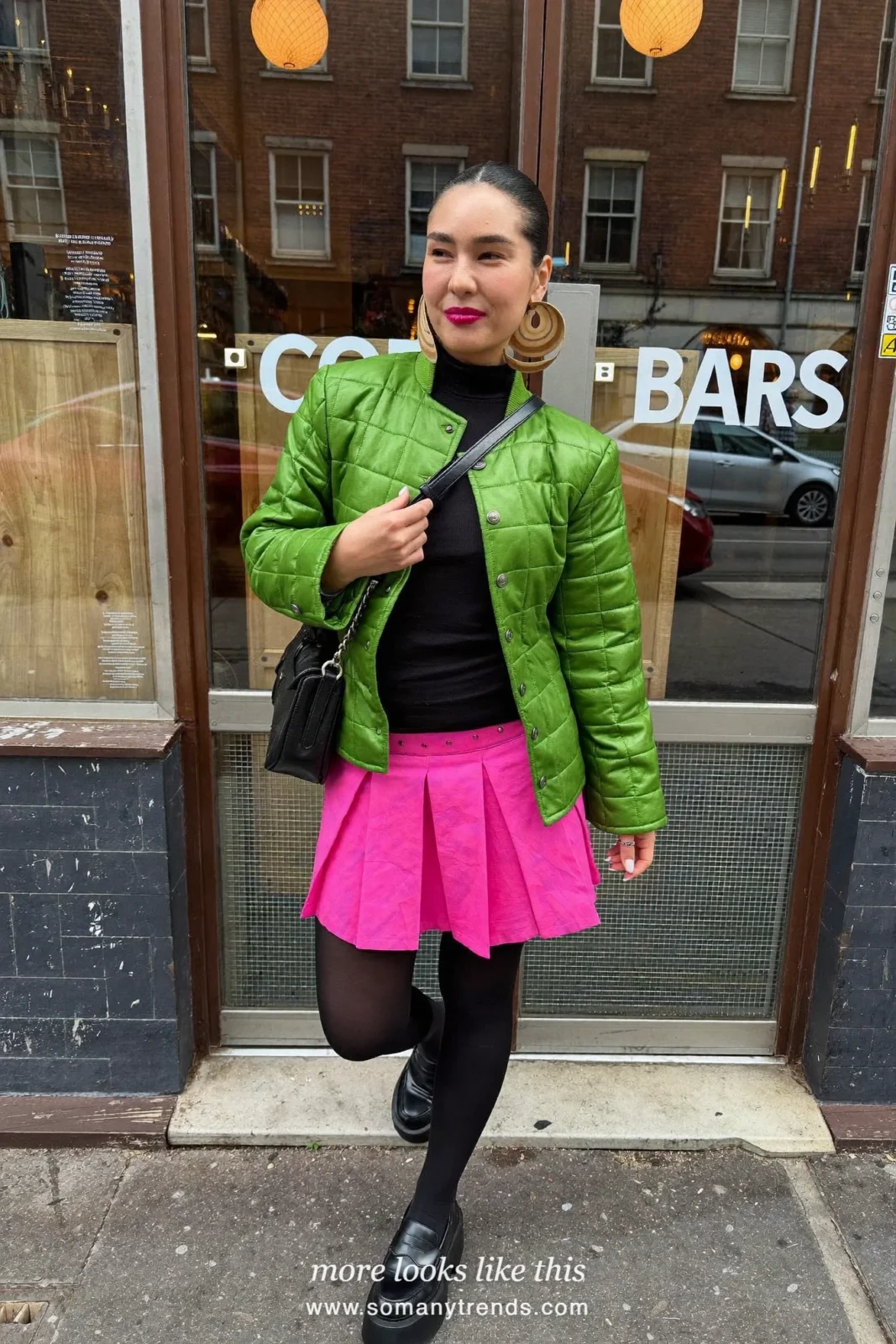 Woman in a moss green quilted jacket, bright pink pleated mini skirt, black opaque tights and platform loafers, outfit 13