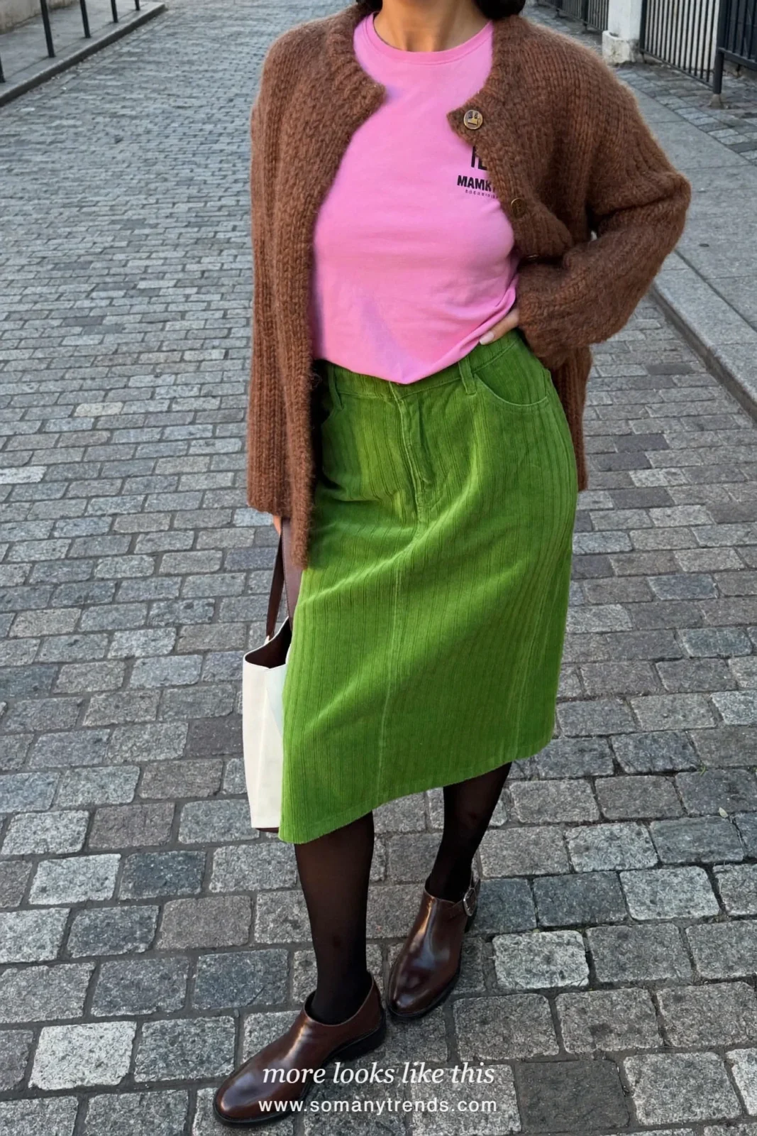 Woman in a bright pink tee, moss green corduroy midi skirt, chocolate brown cardigan and boots, outfit 16