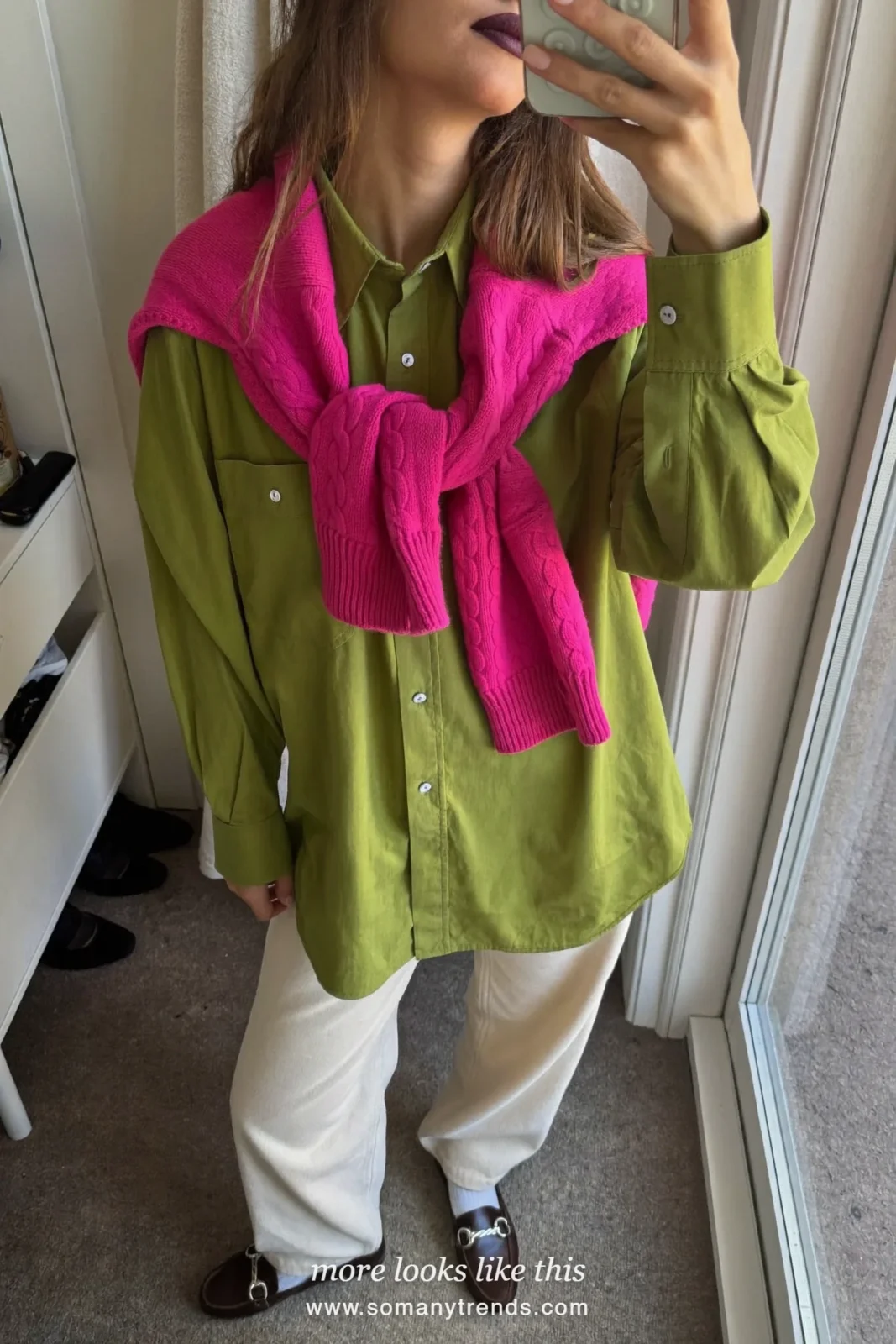 Woman in a moss green shirt with a bright pink sweater tied over the shoulders, cream wide pants and loafers, outfit 21