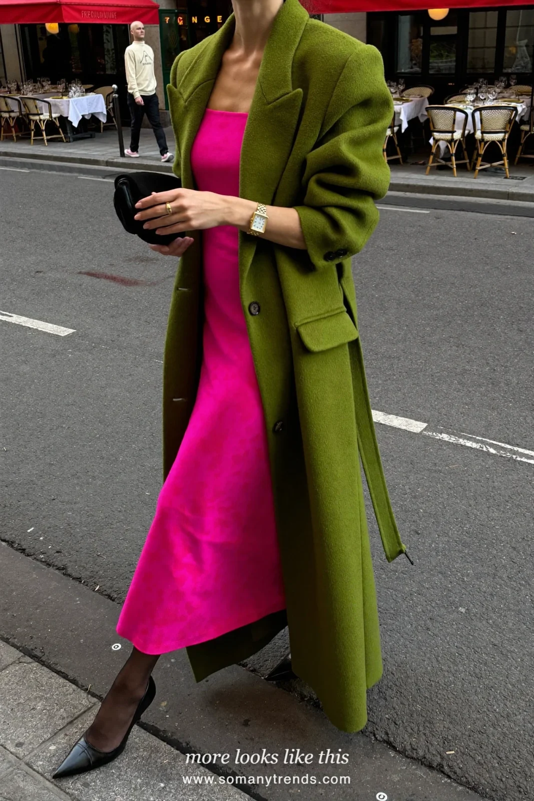 Woman in a moss green long wool coat open over a bright pink midi dress, black tights and pumps, outfit 25
