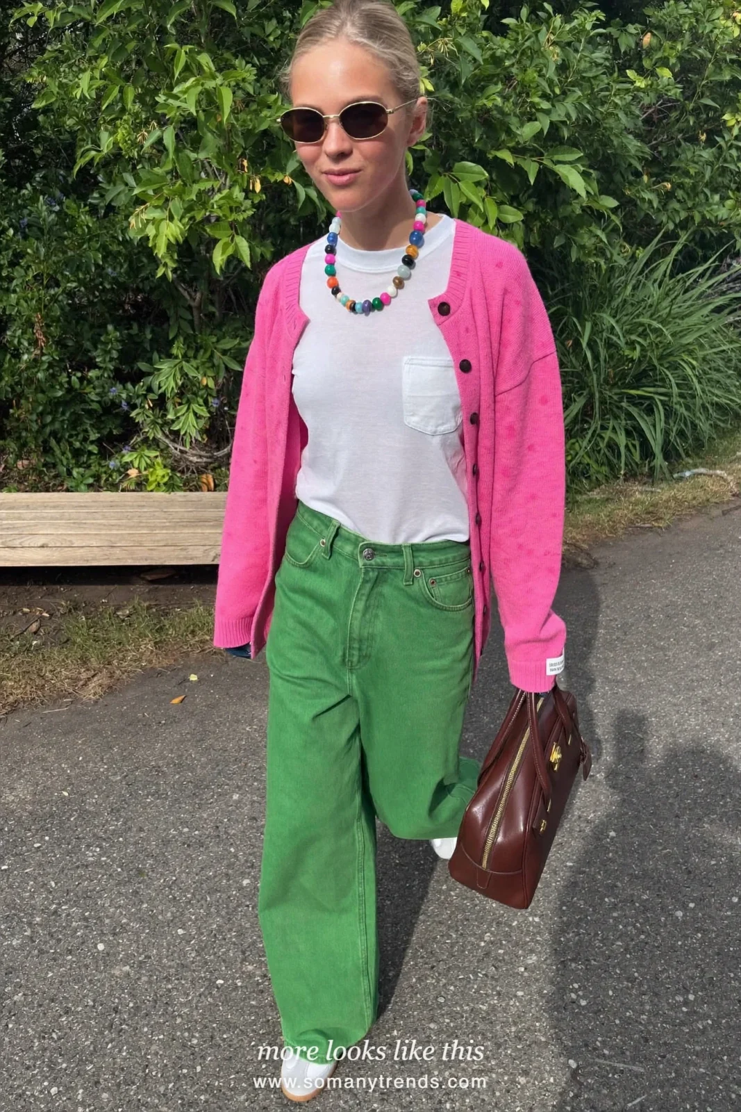 Woman in a bright pink cardigan, white tee, moss green straight jeans and white sneakers with a brown bag, outfit 26